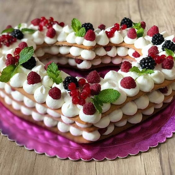 Tort în formă de inimă decorat cu frișcă și fructe de pădure