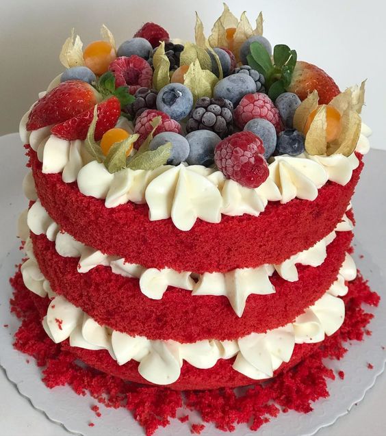 Tort cu blat roz, cu cremă albă, ornat cu frișcă și cu fructe de pădure: mure, zmeură, afine, căpșune